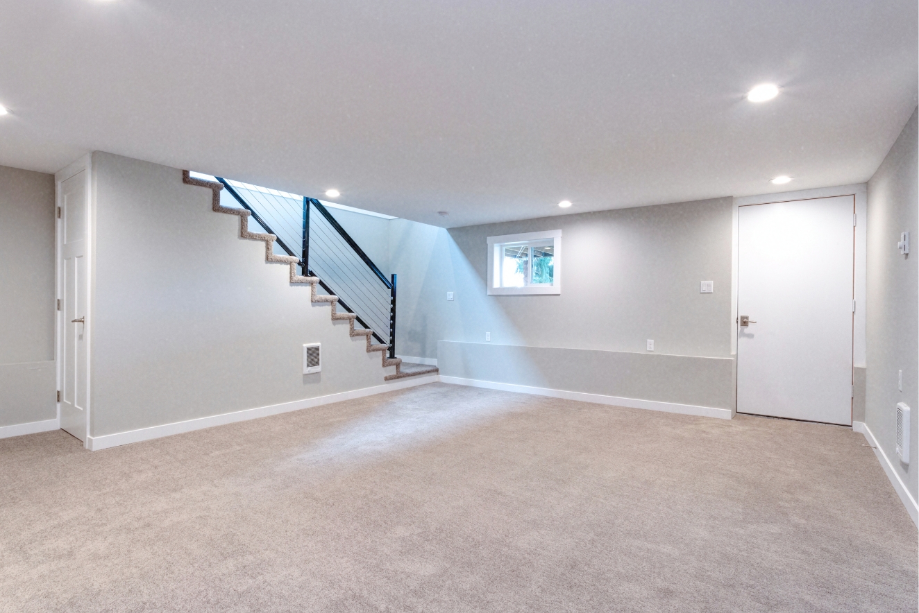 Home organization potential in a clean, spacious basement with white walls, carpeted floor, and stairs, ready for efficient storage and living space solutions.