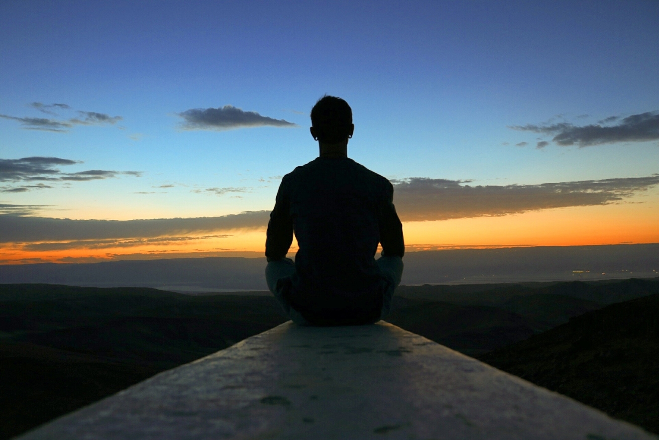 Silhouette of person practicing holistic health through meditation at sunset, embracing mind-body balance